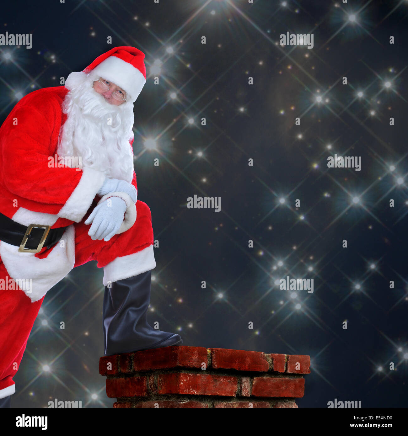 Babbo Natale in piedi su un tetto con un piede sul camino. I suoi bracci sono ripiegati e lui è appoggiata sul suo ginocchio contro un stellata Foto Stock