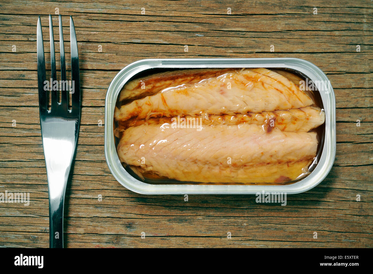 Un open può di conserve di sgombri e una forcella su una tavola in legno rustico Foto Stock