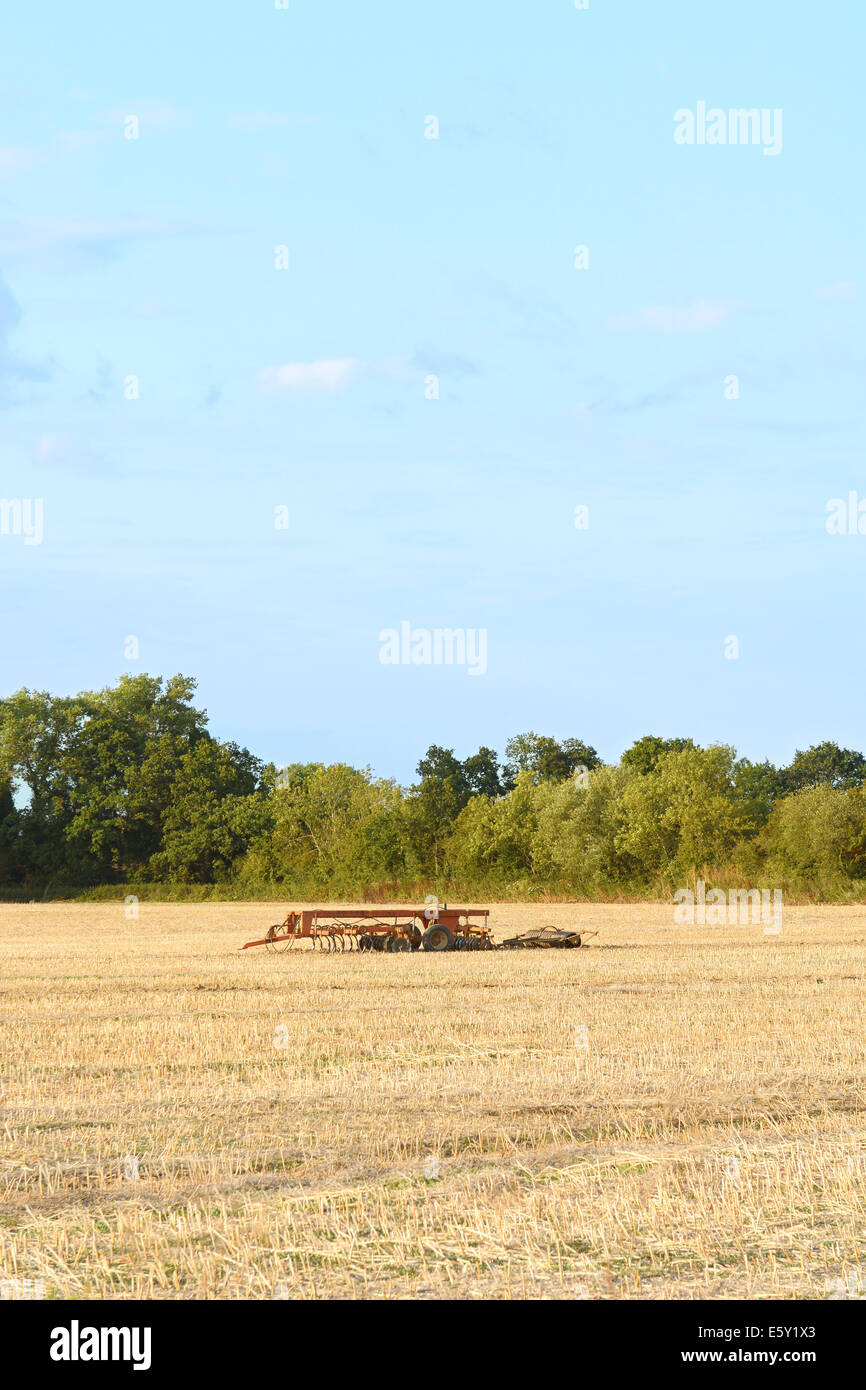 Harrow a sinistra tra la stoppia in un raccolto sul campo di fattoria. Copia nello spazio al di sopra del Cielo di estate blu. Foto Stock