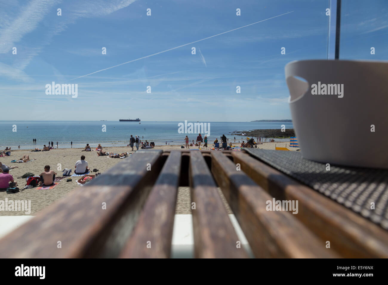 Una vista da Gyllingvase Cafe di tavole in una bellissima spiaggia di sabbia e il cielo blu di Falmouth Beach. Foto Stock