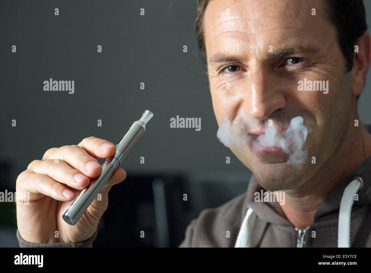 Uomo di fumare sigarette electonic, espirando il fumo Foto Stock