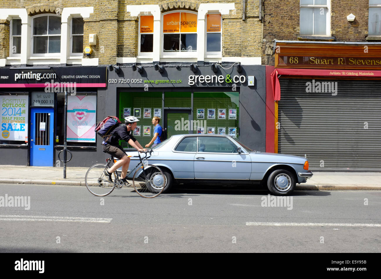 Ciclista passando attorno parcheggiato classic Mercedes Foto Stock