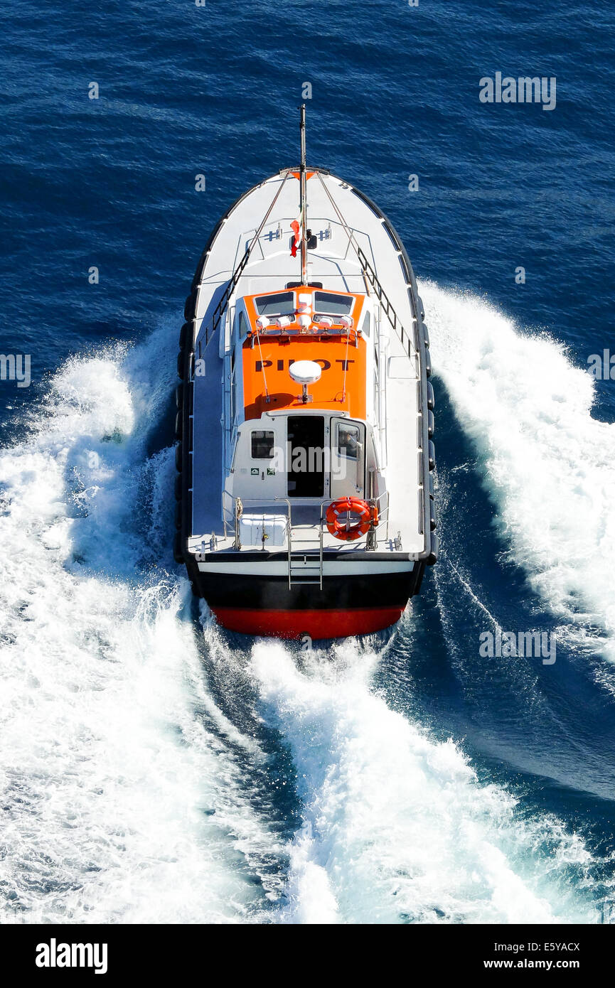 La barca del pilota che aiuta il capitano per entrare e uscire da porte lascia la nave navigazione via con un grande schiuma bianca Foto Stock