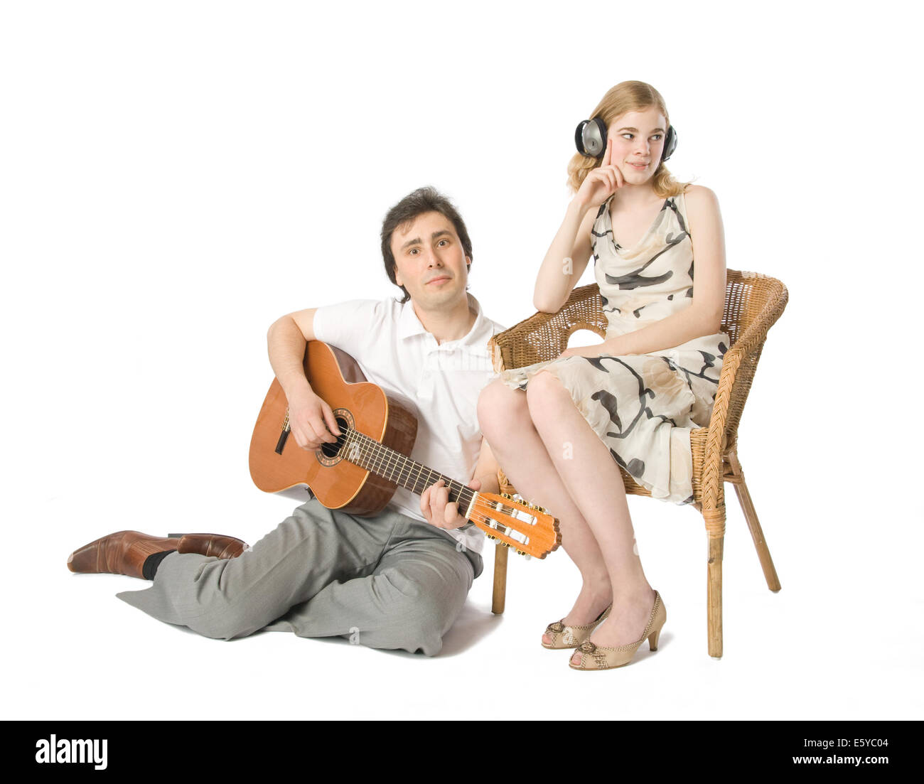 Una donna in cuffie e un uomo a suonare la chitarra per lei Foto Stock