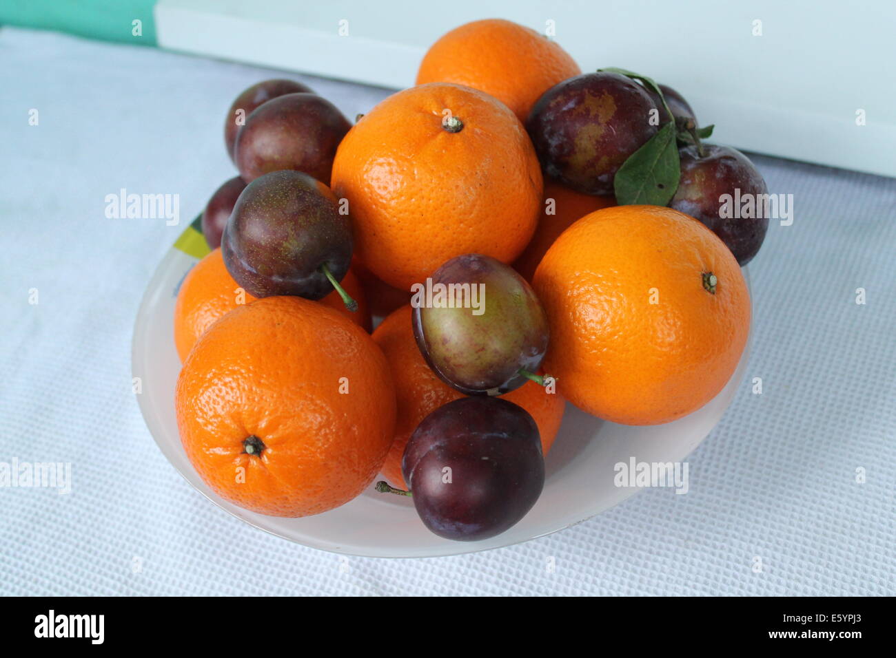 Succoso e freschi frutti maturi di colore arancione di mandarini e polpa dolce di prugne blu dono del giardino estivo Foto Stock
