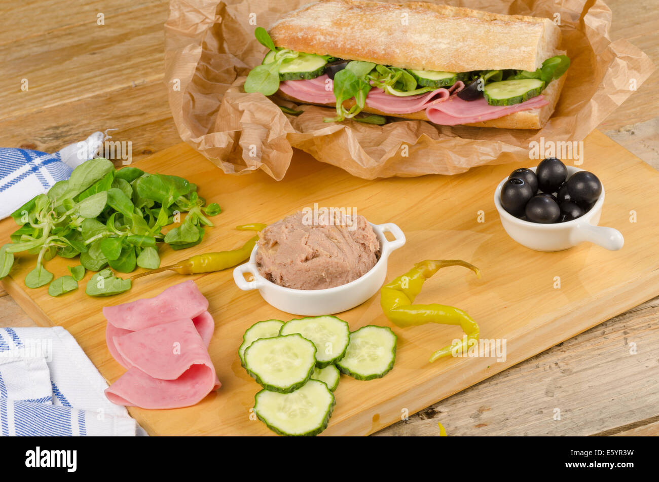 Baguette mediterranea con ingredienti sul tagliere di legno Foto Stock