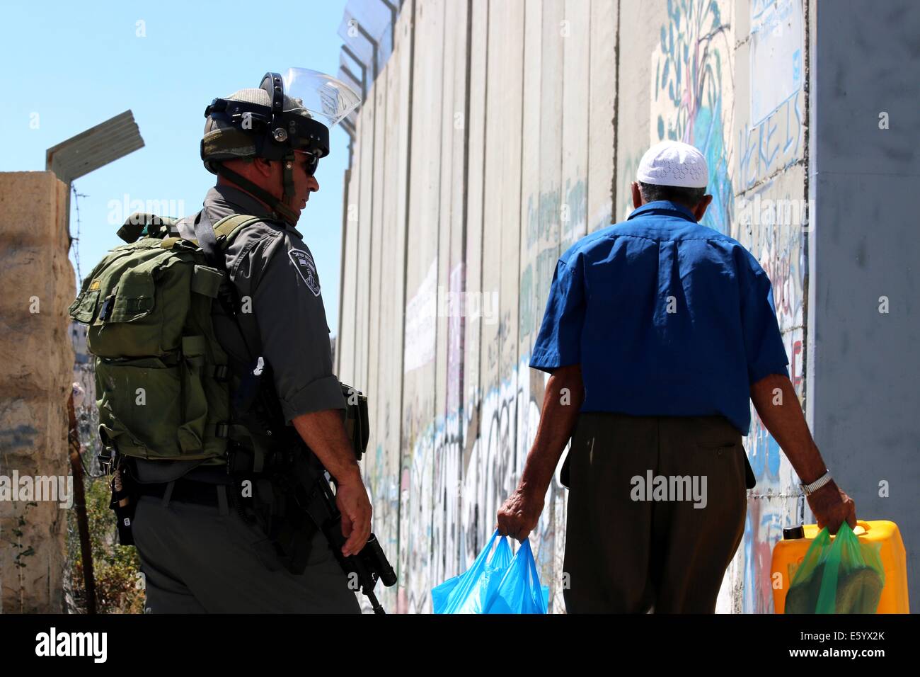 Un anziano uomo palestinese passeggiate ultimi soldati israeliani. Egli fa il suo modo a casa sua in Aida Refugee Camp che si trova vicino alla barriera di separazione. Venerdì pomeriggio è stata dichiarata una rabbia in tutta la Cisgiordania. Nelle prime ore del mattino, dopo 8 A.m., la 72 Ore di cessate il fuoco tra Gaza e Israele si è conclusa e lottare contro la ripresa. Nelle prime ore della sera le forze israeliane hanno sparato e ucciso Ahmad Mohammad al-Qatar da al Amari Refugee Camp vicino a Ramallah, come le proteste hanno continuato nella solidarietà per la Striscia di Gaza in Cisgiordania. Oltre 40 persone sono rimaste ferite a Hebron durante le proteste. Nel frattempo, le incursioni aeree israeliane ucciso Foto Stock