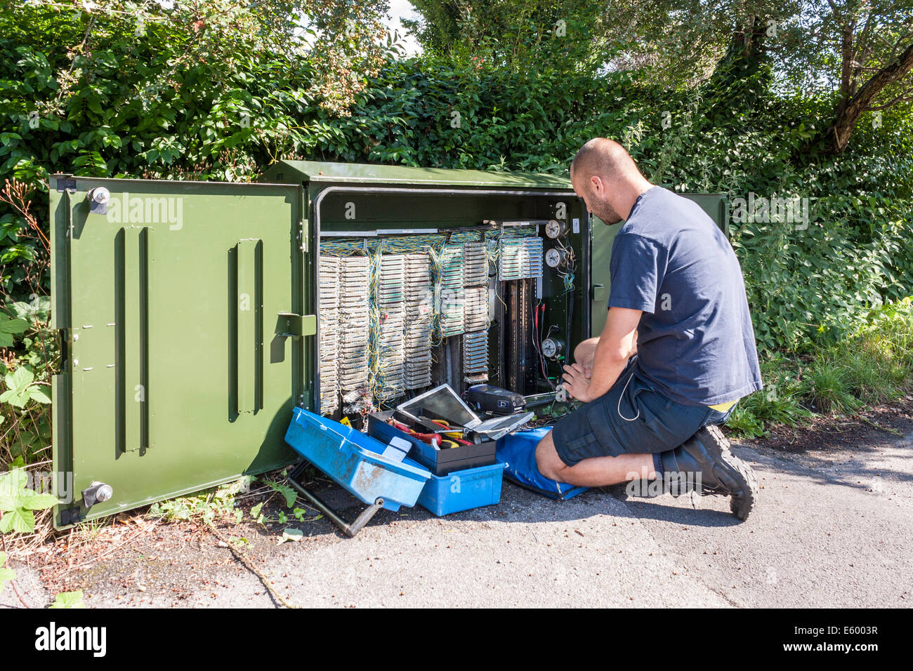 Ingegnere di lavoro per BT Openreach corregge le anomalie a banda larga ad un terminale sul lato della strada. Foto Stock
