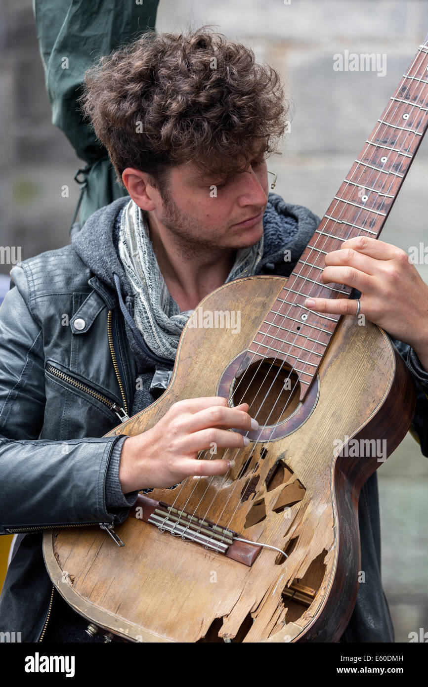 Suonatore ambulante di strada la riproduzione di un vecchio e chitarra danneggiato durante la Edinburgh Fringe Festival di Edimburgo, Scozia, Regno Unito Foto Stock