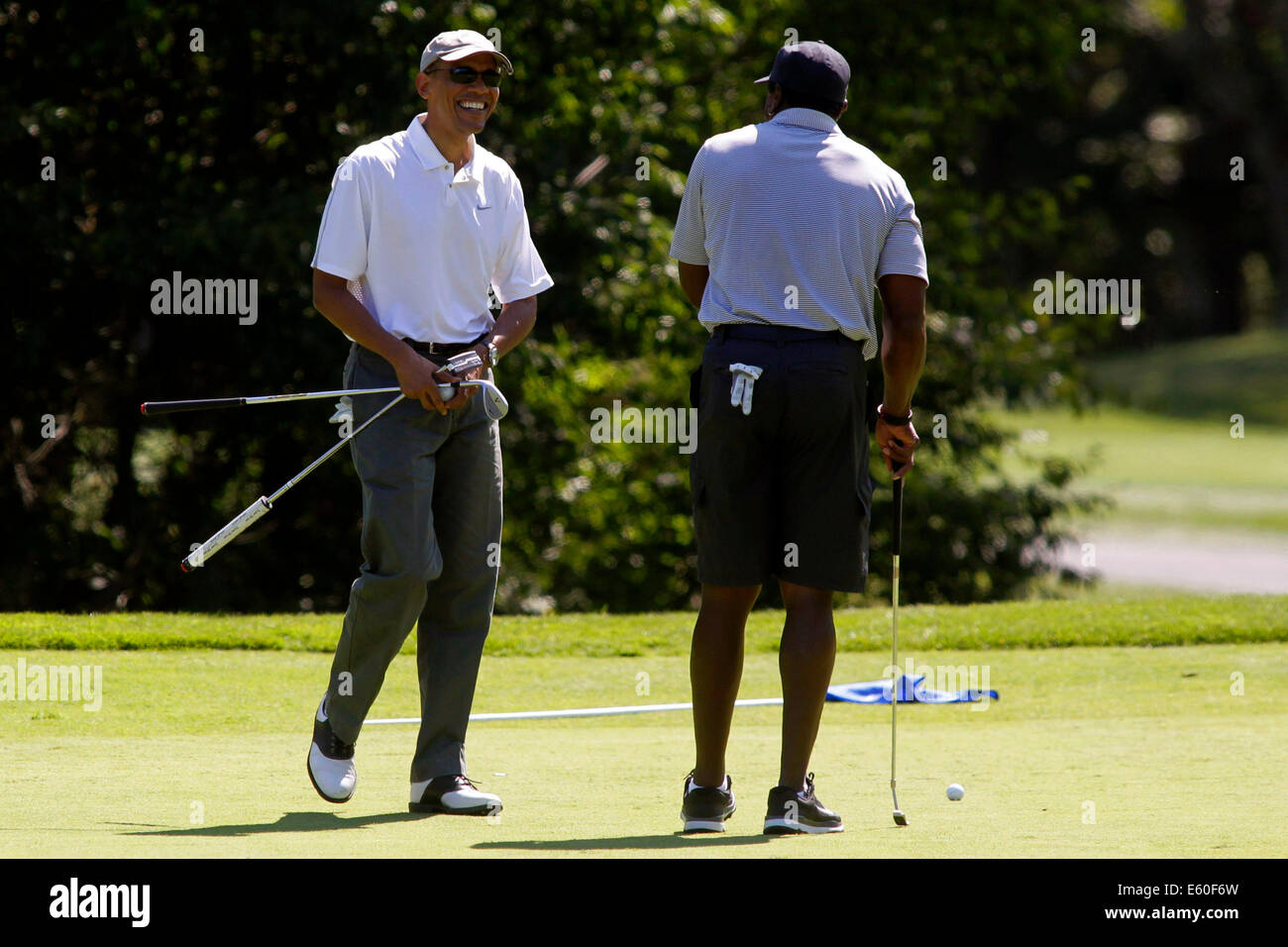 Oak Bluffs, Massachusetts, STATI UNITI D'AMERICA. Il 9 agosto, 2014. Il Presidente degli Stati Uniti Barack Obama, sinistra, ride dopo Ahmad Rashad realizzato un putt sul primo green presso la fattoria collo Golf Club in Oak Bluffs, Massachusetts, STATI UNITI, Sabato, Agosto 9, 2014. Il Presidente arrivati sull'isola oggi e che è in vacanza per due settimane. Credito: Matthew Healey/Piscina via CNP - NESSUN SERVIZIO DI FILO- Credito: dpa/Alamy Live News Foto Stock