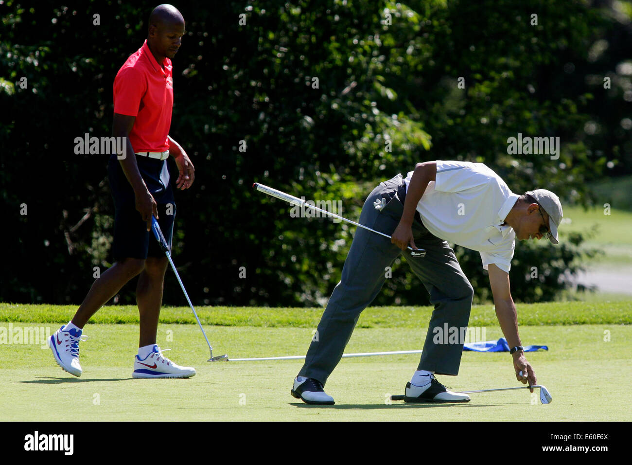 Oak Bluffs, Massachusetts, STATI UNITI D'AMERICA. Il 9 agosto, 2014. Il Presidente degli Stati Uniti Barack Obama, destra, preleva un club durante la riproduzione di un round di golf con Ray Allen, a sinistra sul primo green presso la fattoria collo Golf Club in Oak Bluffs, Massachusetts, Stati Uniti, sabato 9 agosto 2014. Il Presidente è in vacanza sull'isola per due settimane. Credito: Matthew Healey/Piscina via CNP - NESSUN SERVIZIO DI FILO- Credito: dpa/Alamy Live News Foto Stock