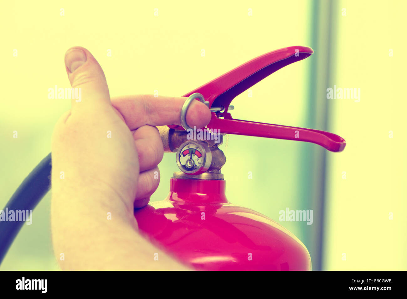 Mano bianca tira il perno dall'estintore Foto Stock