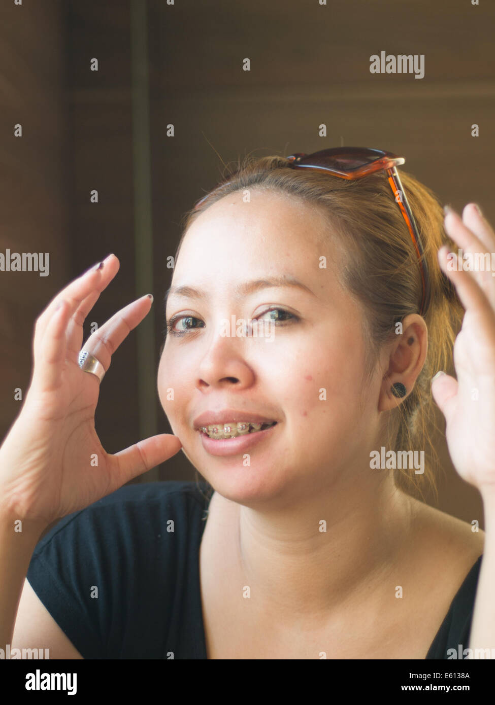 Giovane donna asiatica con occhiali da sole sorridente in natura Foto Stock