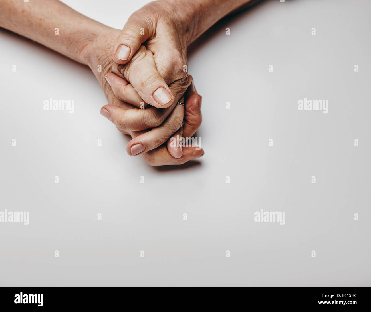 Senior donna di mani isolato su sfondo grigio. Le mani di un vecchio rilassato femmina con copia spazio. Pregando le mani. Foto Stock