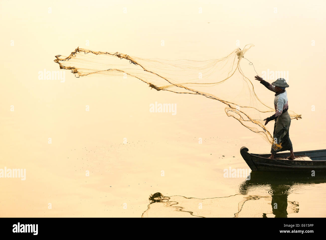 Pescatore in una barca nel lanciare un net, la luce del mattino, Lago Thaungthaman, Amarapura, Mandalay Division, Myanmar Foto Stock