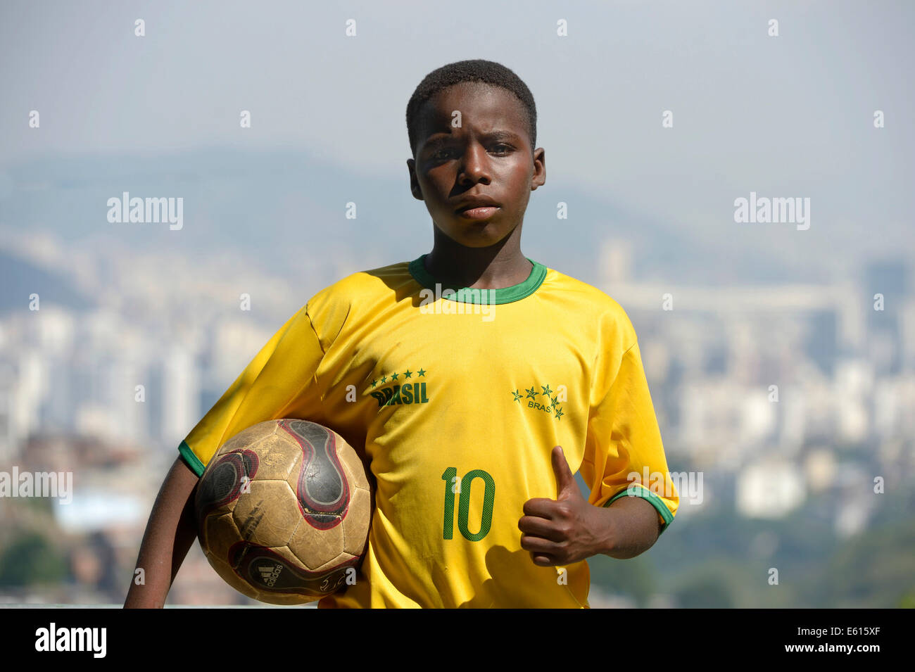 Il ragazzo, 13 anni, indossando la maglia della nazionale brasiliana, tenendo un calcio, Rio de Janeiro, Brasile Foto Stock