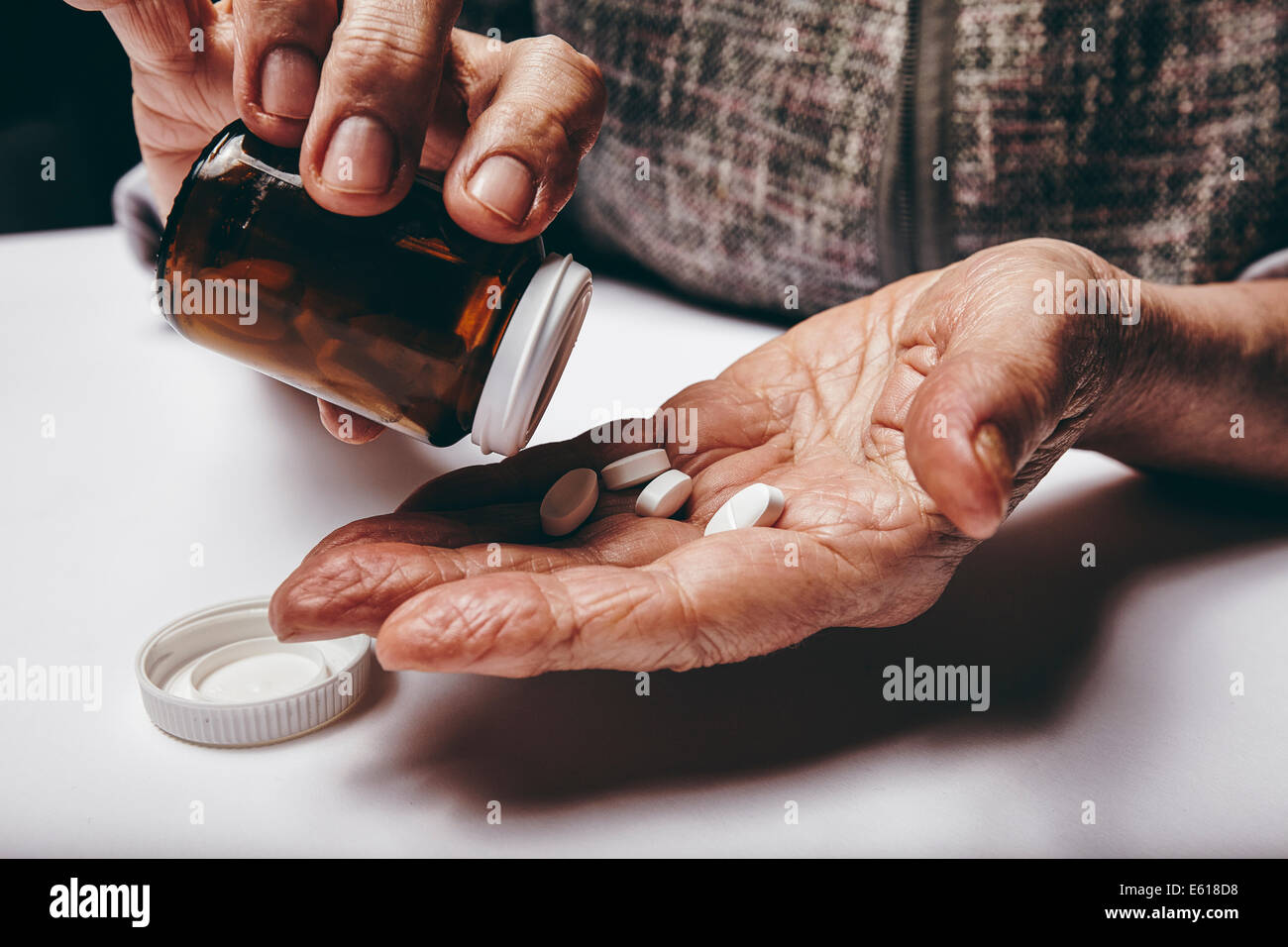 Close-up immagine della donna senior di prendere pillole dal flacone di pillole. Concentrarsi sulle mani. Il vecchio donna assumendo medicinali. Foto Stock