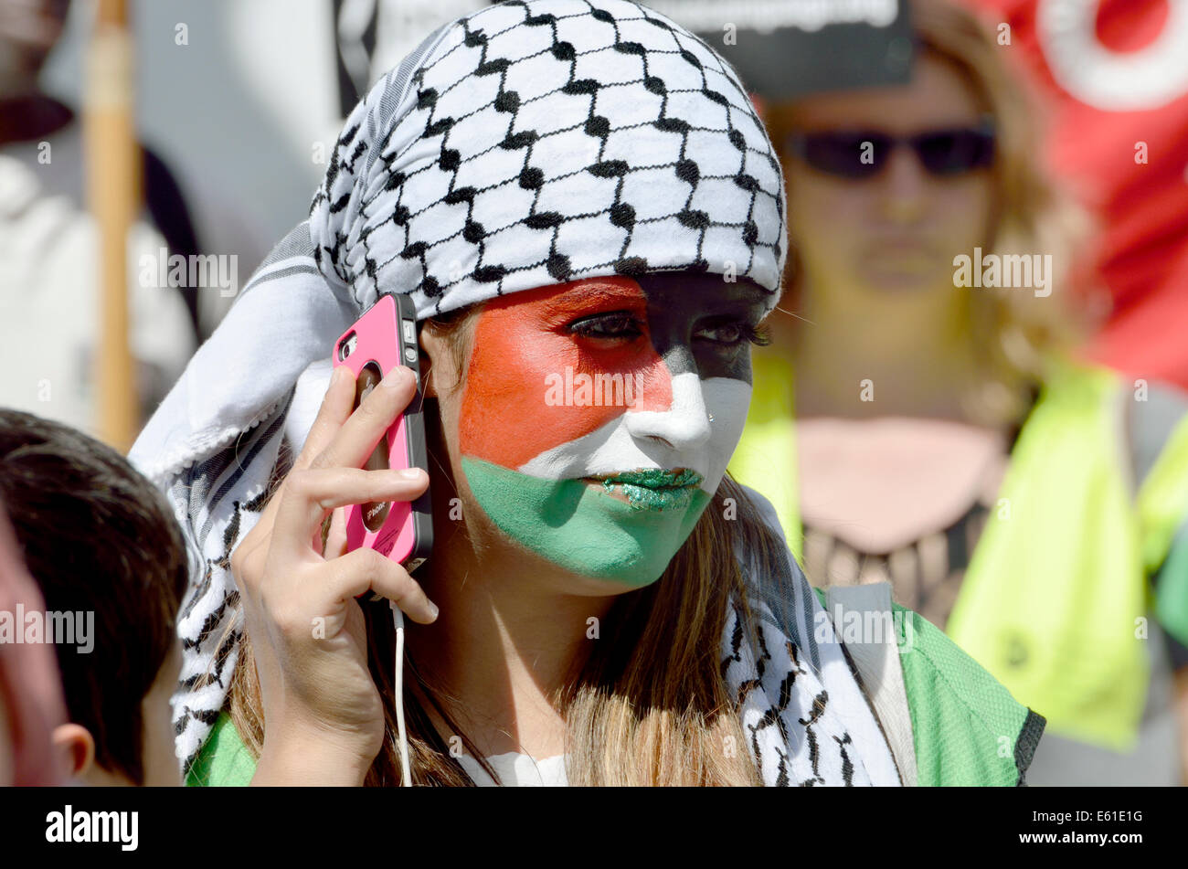 Giovane donna con il volto dipinto con i colori della bandiera palestinese a marzo per Gaza, Londra, 9 Agosto 2014 Foto Stock