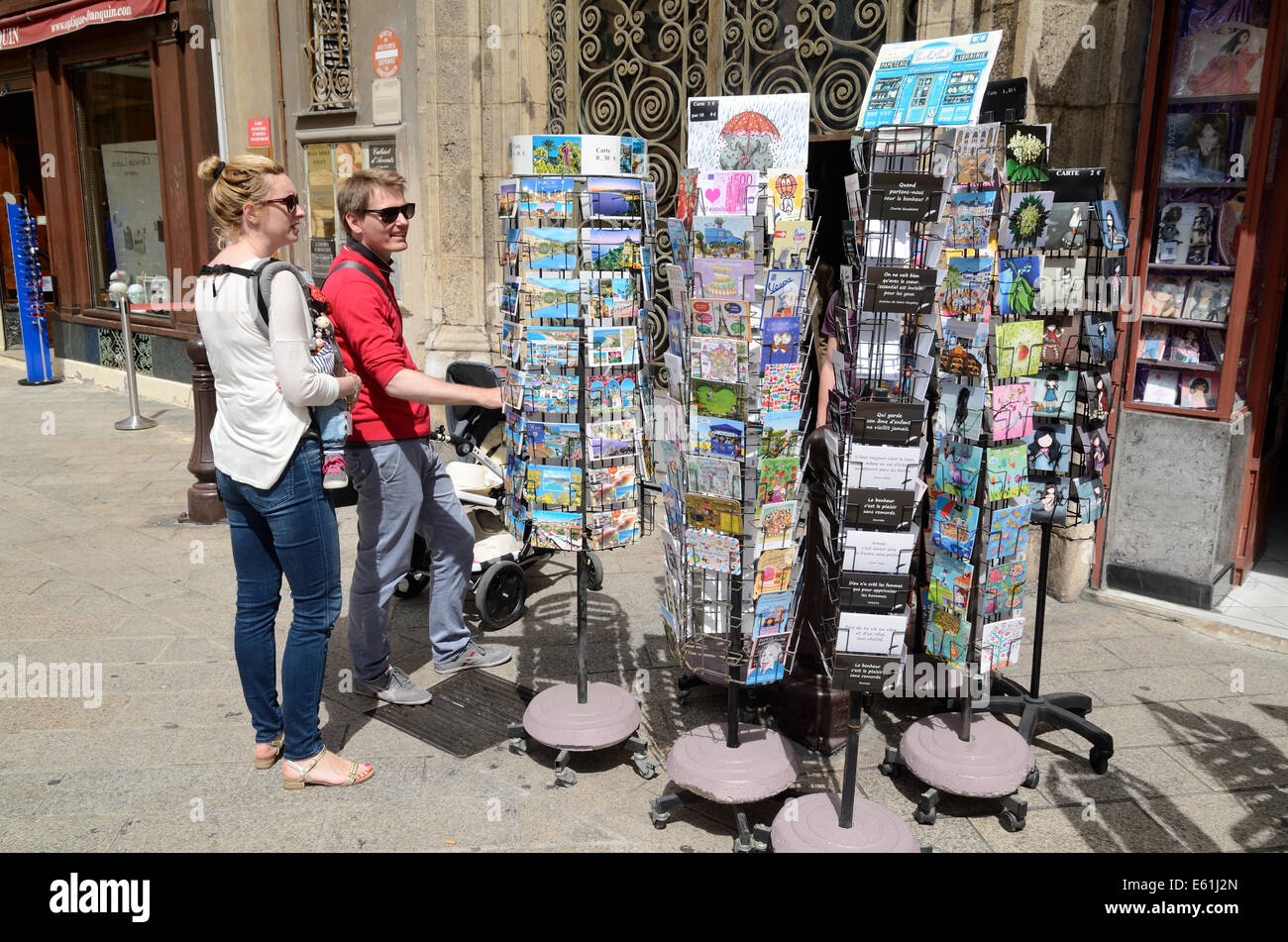 I turisti la scelta di cartoline al di fuori di un negozio di Souvenir o regali in Nizza Alpi Marittime Francia Foto Stock