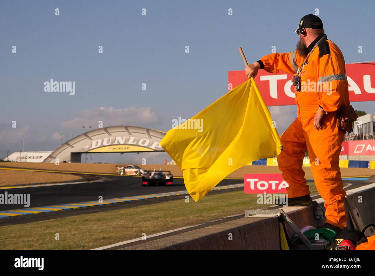 Il maresciallo di bandiera sventola bandiera gialla a ponte Dunlop Le Mans 24 ore di gara 2014 Foto Stock