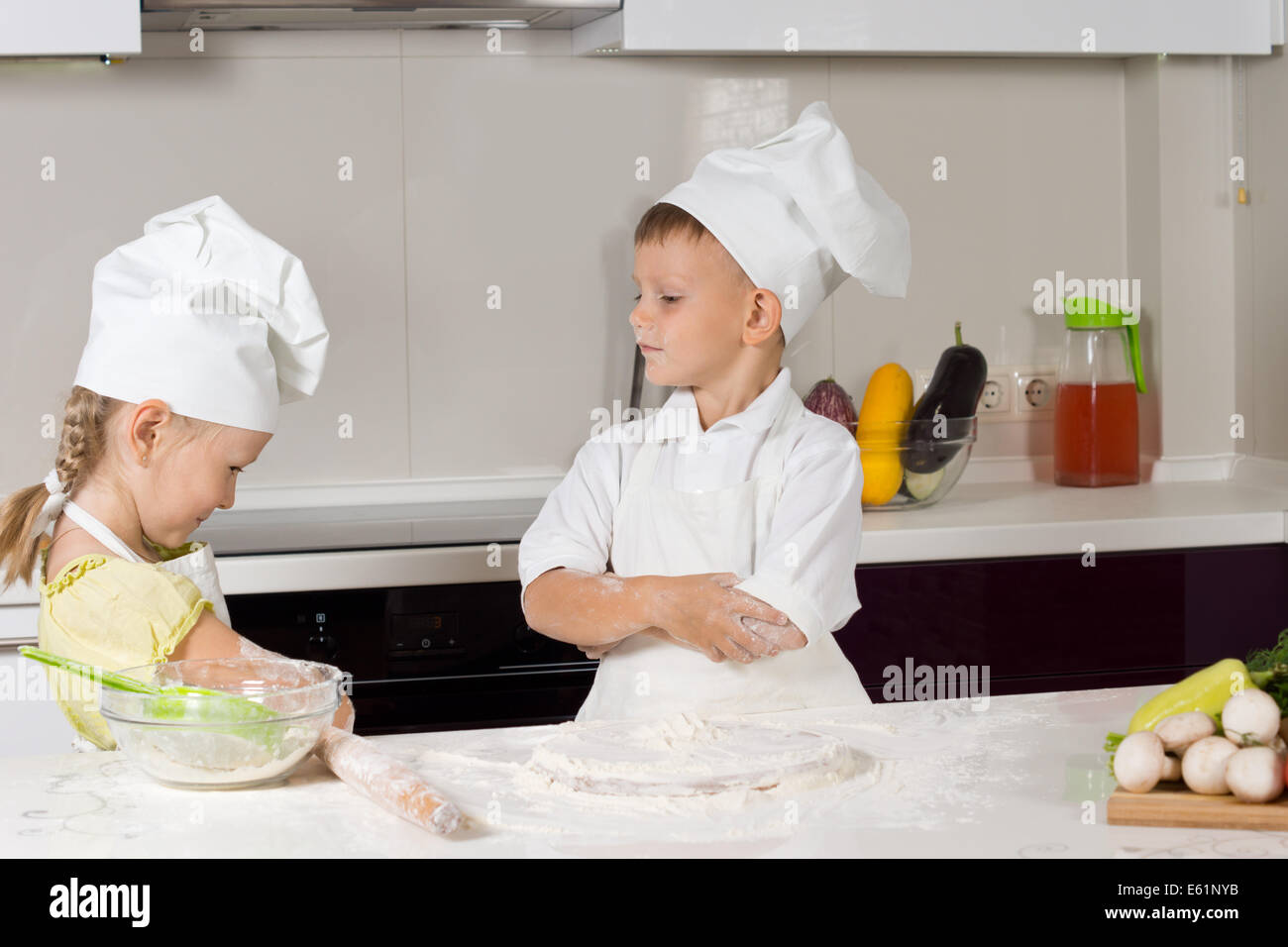Due giovani chef simpatico gioco di ruolo presso la cucina domestica. Foto Stock