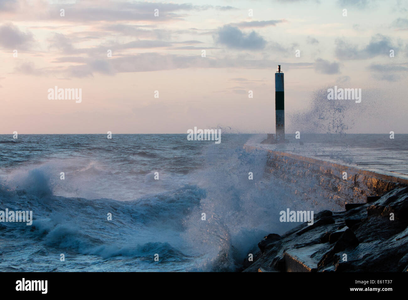 Aberystwyth, Wales, Regno Unito. 11 Ago, 2014. Il mare agitato dalla tempesta chiamato Bertha onde si blocca contro il faro in Aberystwyth al tramonto. Credito: Jon Freeman/Alamy Live News Foto Stock