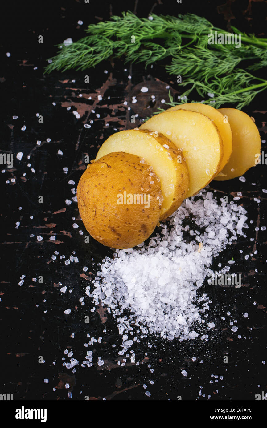 Fette di patate bollite con sale marino e aneto su tavoli in legno nero Foto Stock