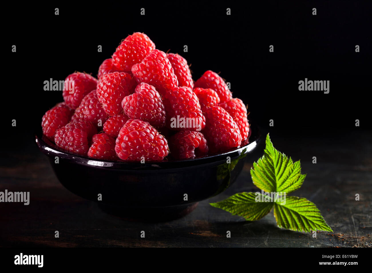 Ciotola di lamponi freschi su sfondo scuro Foto Stock