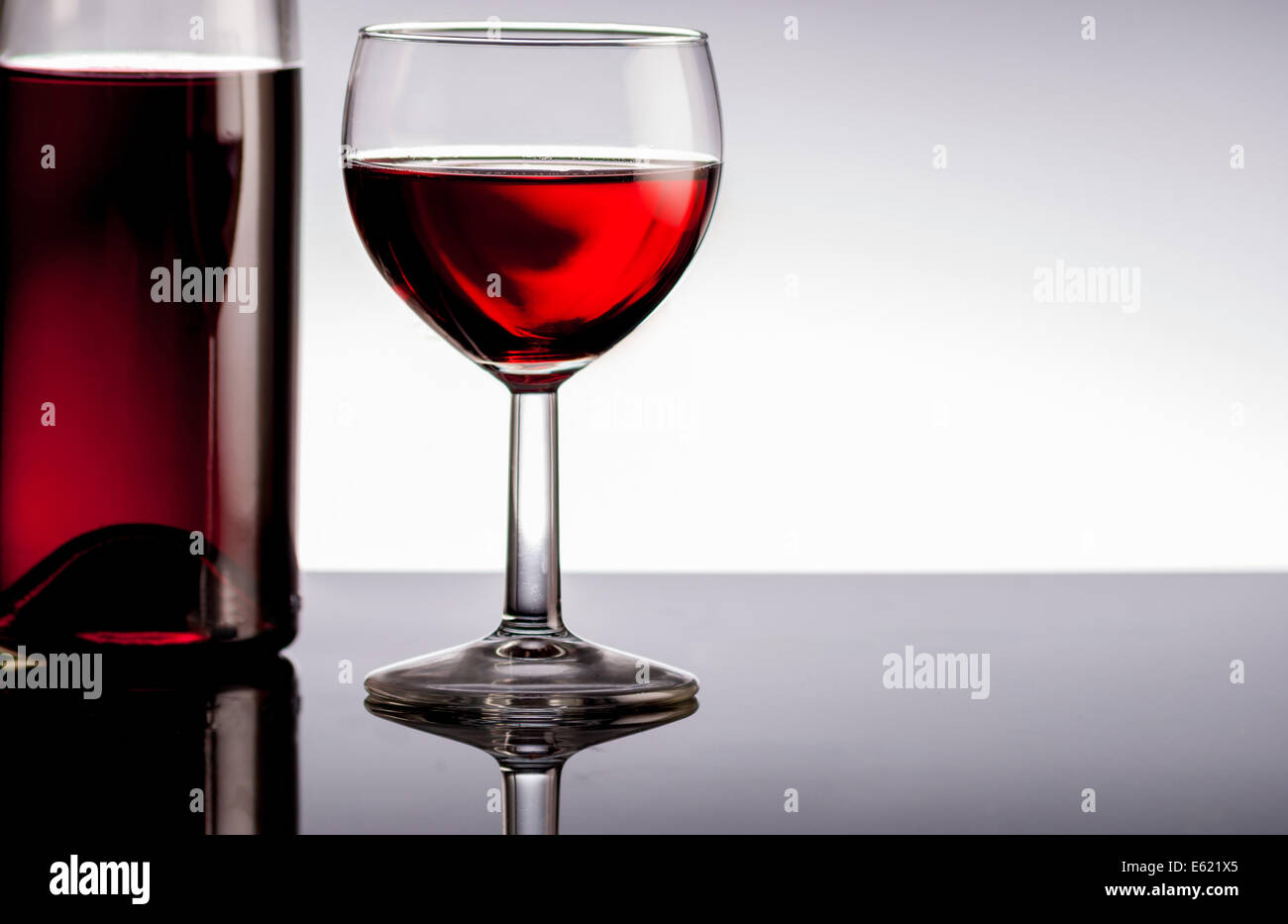 Vino rosso in bottiglia su nero riflettere sullo sfondo Foto Stock