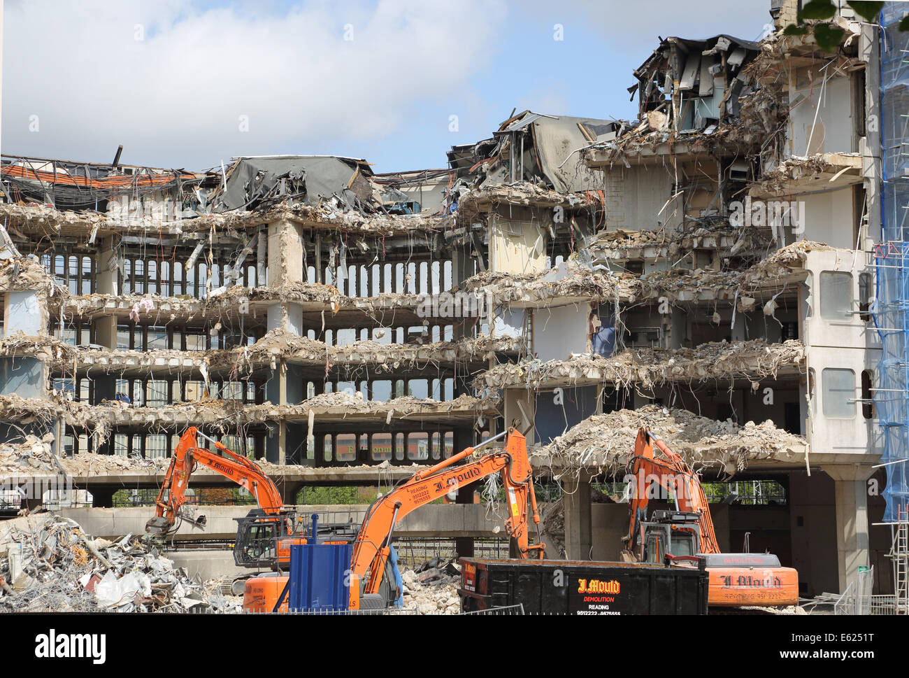 Un edificio a sei piani in cemento armato edificio ufficio in lettura è demolita utilizzando idraulico, escavatori cingolati Foto Stock