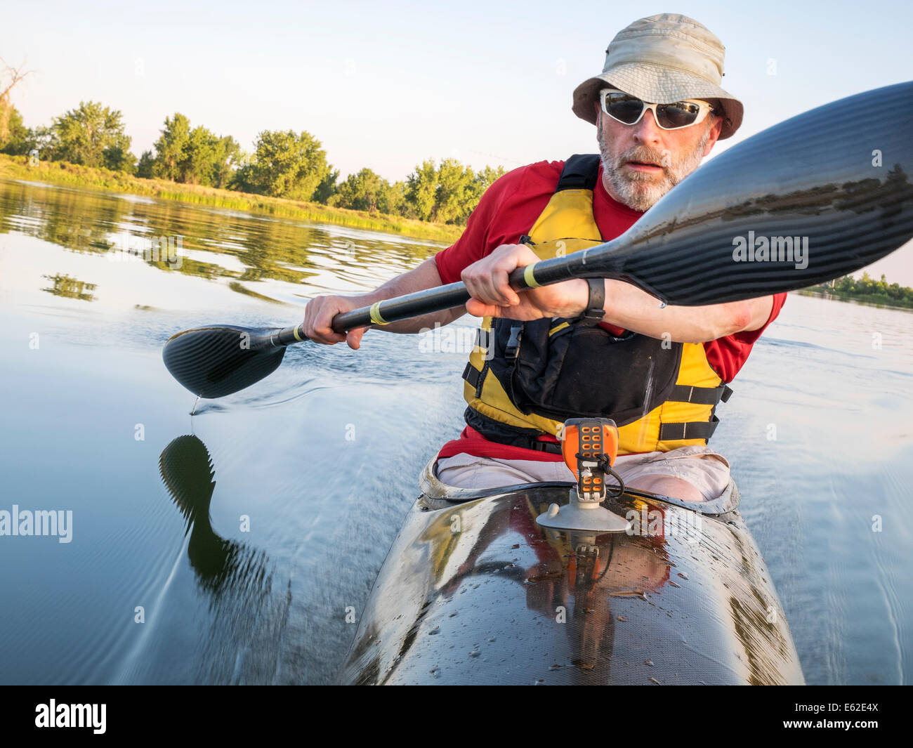 Senior maschio è sguazzare un fast racing kayak di mare con una paletta di parafango su di un lago calmo, Fort Collins, Colorado Foto Stock