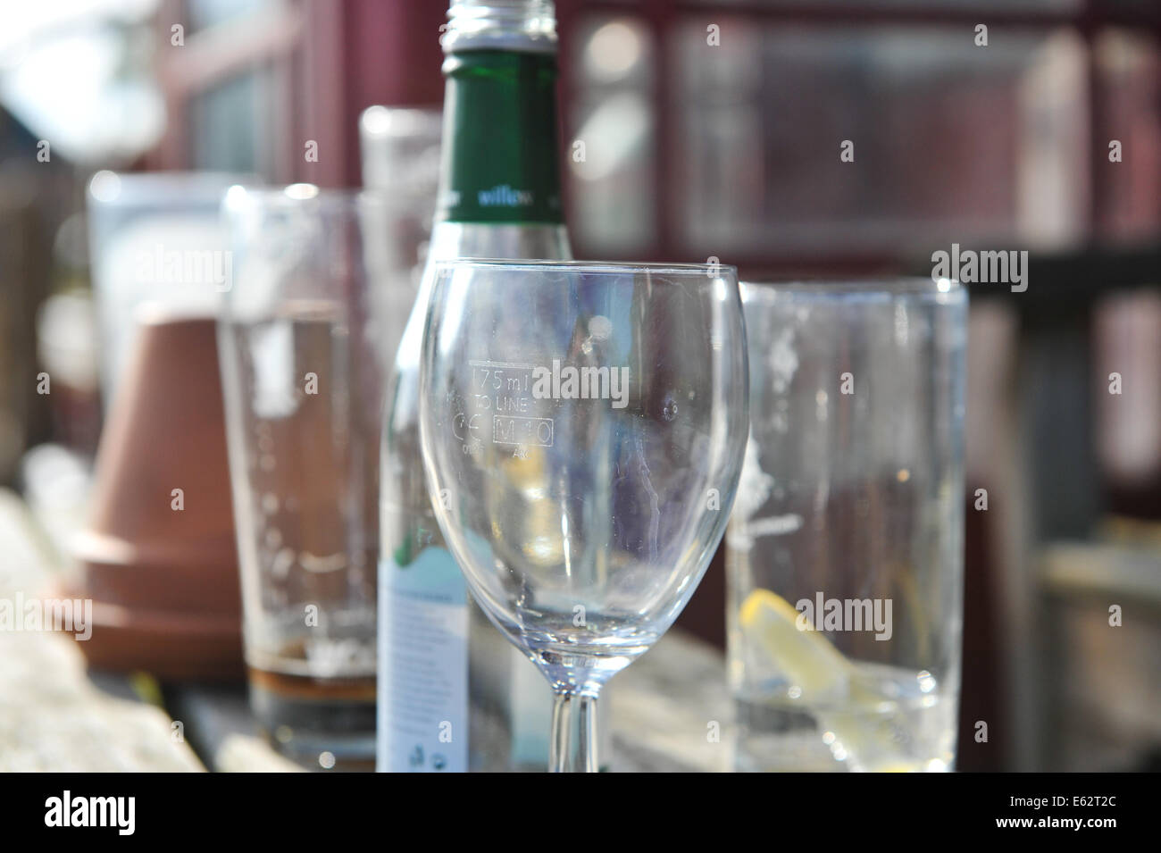 Bicchiere da vino vuote le bottiglie di vetro, birra vetro su un tavolo al di fuori di un pub Foto Stock