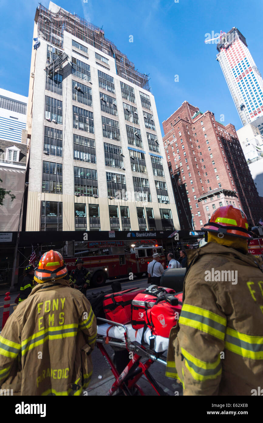 Manhattan, New York. I membri del reparto antincendio osservare un incidente di lavoro su un edificio.scale e motori pronto a intervenire Foto Stock
