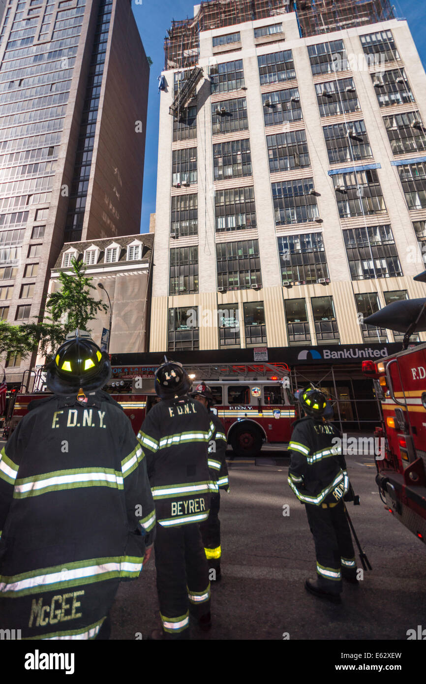 Manhattan, New York. I membri del reparto antincendio osservare un incidente di lavoro su un edificio.scale e motori pronto a intervenire Foto Stock