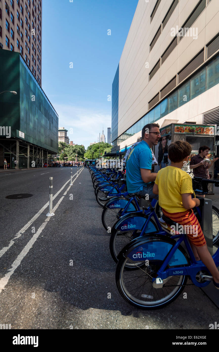 Manhattan, New York. Un uomo e suo figlio sedersi sulla moto in un 'Citi bike stazione". Foto Stock