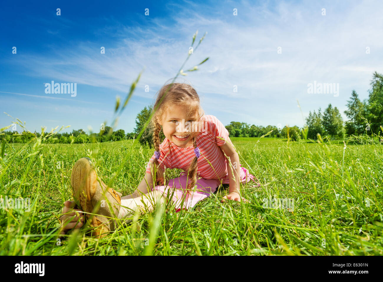 Felice ragazza rendendo gamba-split su erba in estate Foto Stock