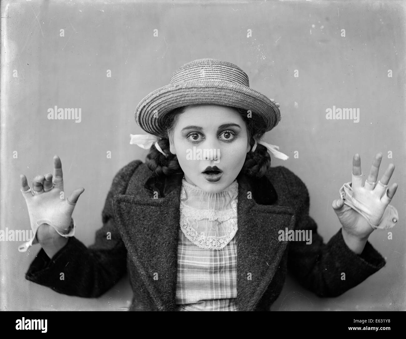 1910s 1920 SORPRESO STARTLED ragazza adolescente con pig-tail indossando cappello di paglia guanti giacca guardando la telecamera SILENT MOVIE ANCORA Foto Stock