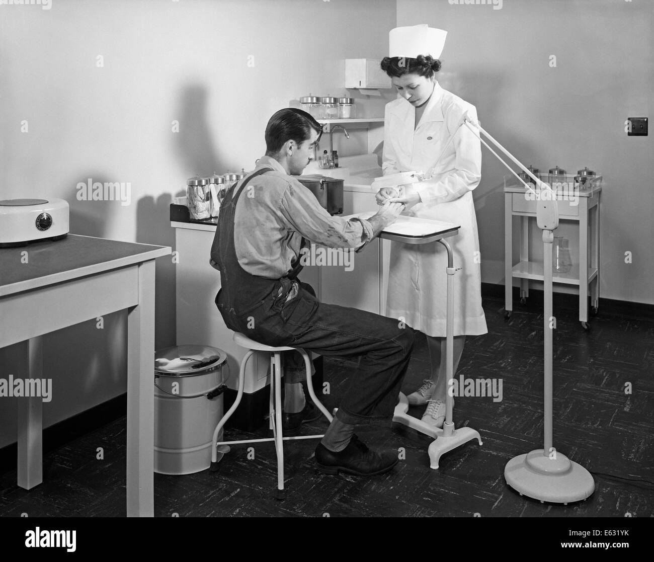 Negli anni quaranta anni cinquanta infermiere esaminare il pregiudizio sulla mano di uomo in infermeria in fabbrica Foto Stock