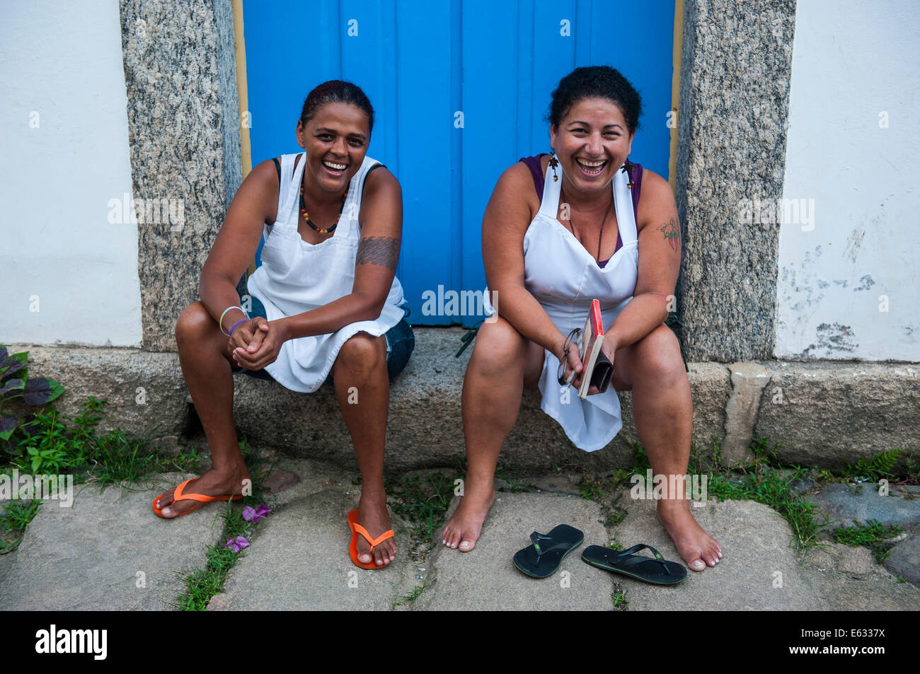 Due donne amichevole seduti sulla soglia di casa, Paraty, Stato di Rio de Janeiro, Brasile Foto Stock
