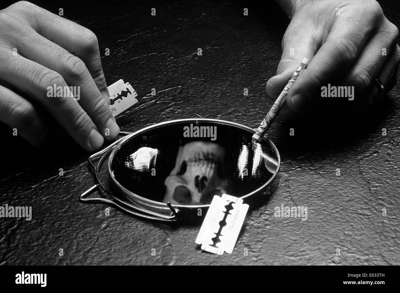 Mani tenendo la lama di un rasoio e arrotolato a $20.00 BILL OLTRE LO SPECCHIO COPERTO CON LA COCAINA E LA RIFLESSIONE DI MORTE teschio di testa Foto Stock