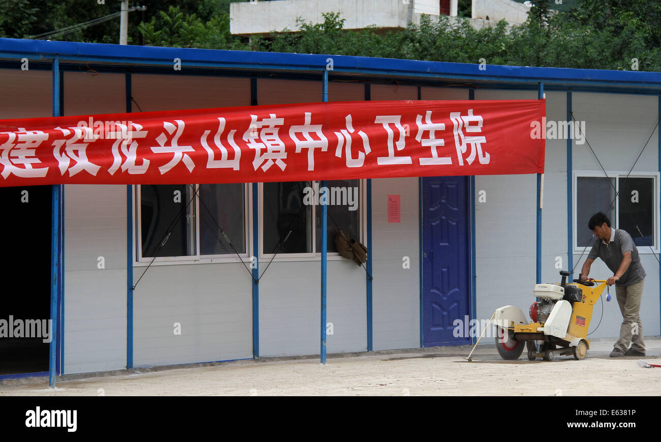 Ludian cinese della provincia dello Yunnan. 13 Ago, 2014. Un lavoratore cancella la massa del primo ospedale di fortuna costruiti dopo il 6,5-terremoto di magnitudine Longtoushan nella città di Ludian County, a sud-ovest della Cina di Provincia di Yunnan, Agosto 13, 2014. L'ospedale di fortuna, che può ospitare fino a 50 pazienti ospedalizzati e 150 pazienti della clinica, è stato messo in servizio il mercoledì. Credito: Pei Xin/Xinhua/Alamy Live News Foto Stock