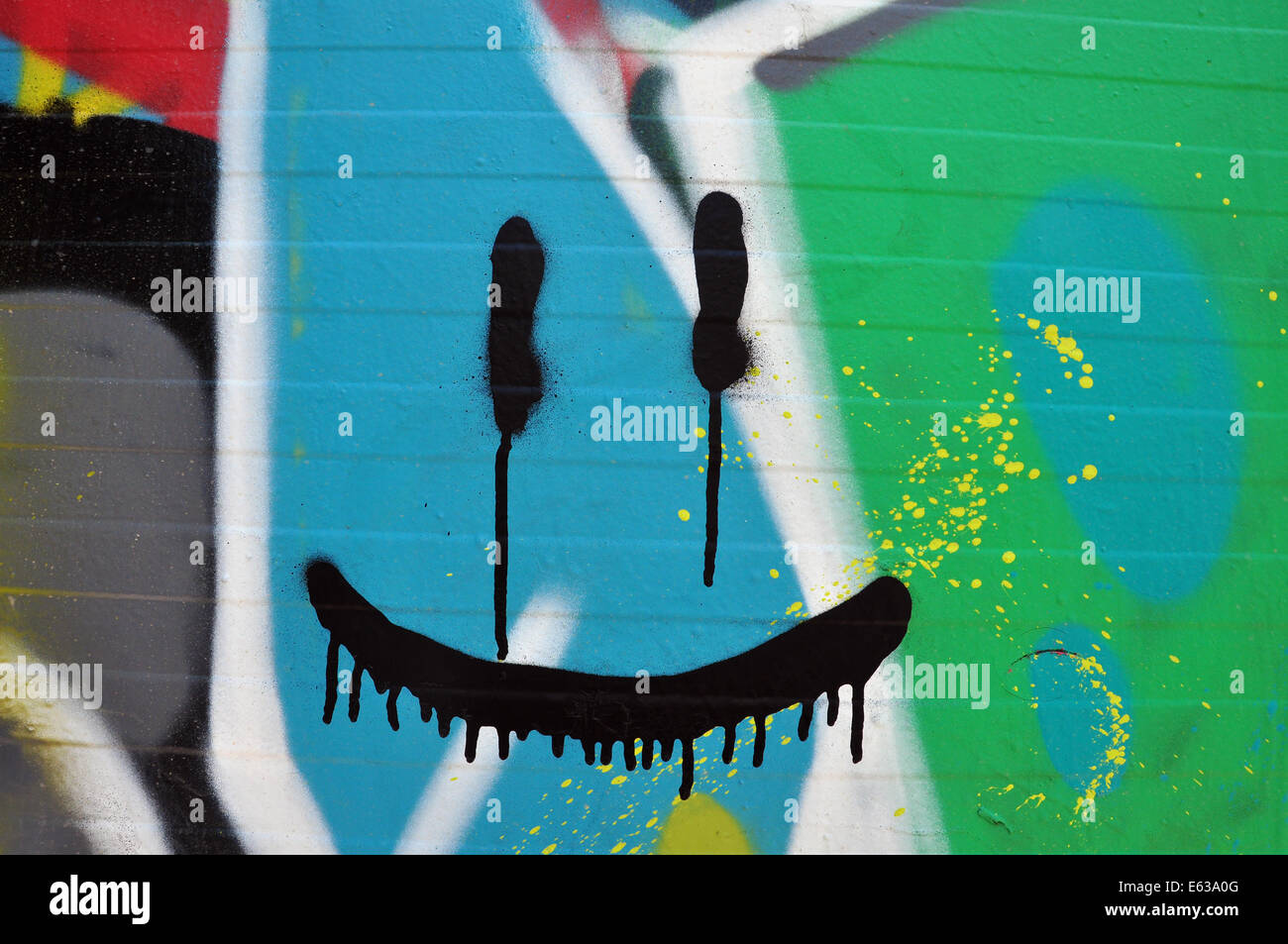 Abstract faccia sorridente sul muro con colorati graffiti e schizzato vernice. Foto Stock
