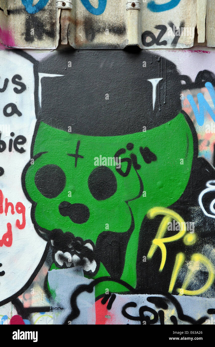 Cranio verde verniciato a spruzzo su un muro coperto di graffiti e tag. Strada urbana art. Foto Stock