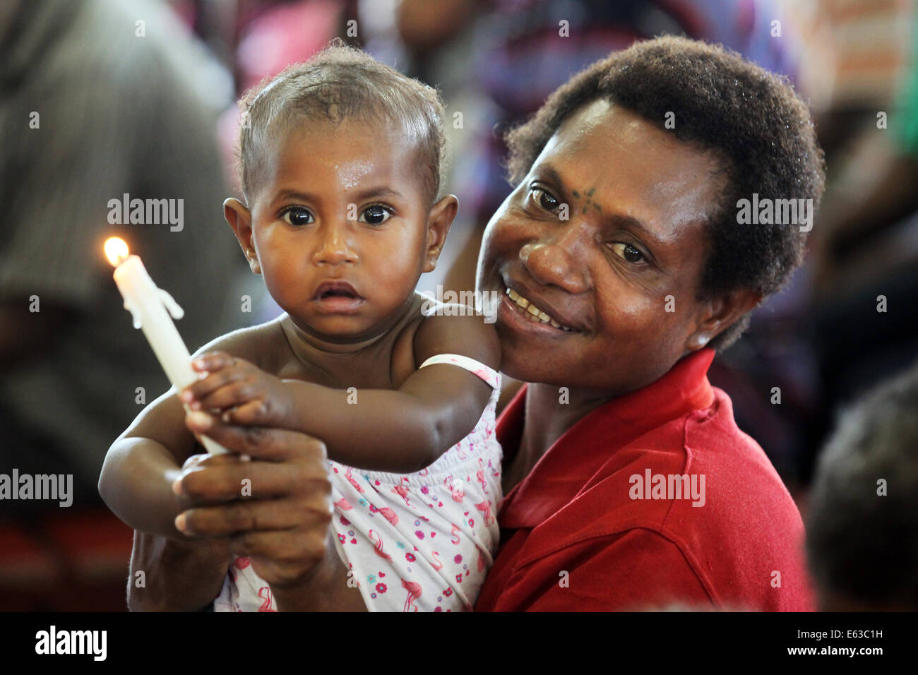 Madre con ragazza giovane azienda candela in una chiesa di Kiunga, Papua Nuova Guinea Foto Stock