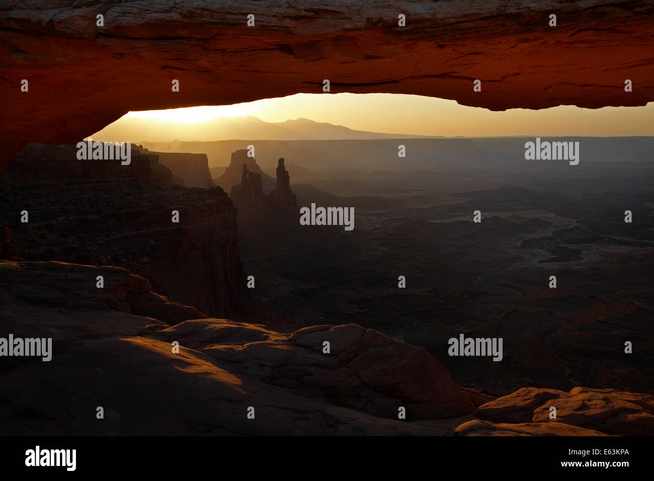 Sunrise oltre La Sal Mountains e sotto Mesa Arch, il Parco Nazionale di Canyonlands, Utah, Stati Uniti d'America Foto Stock