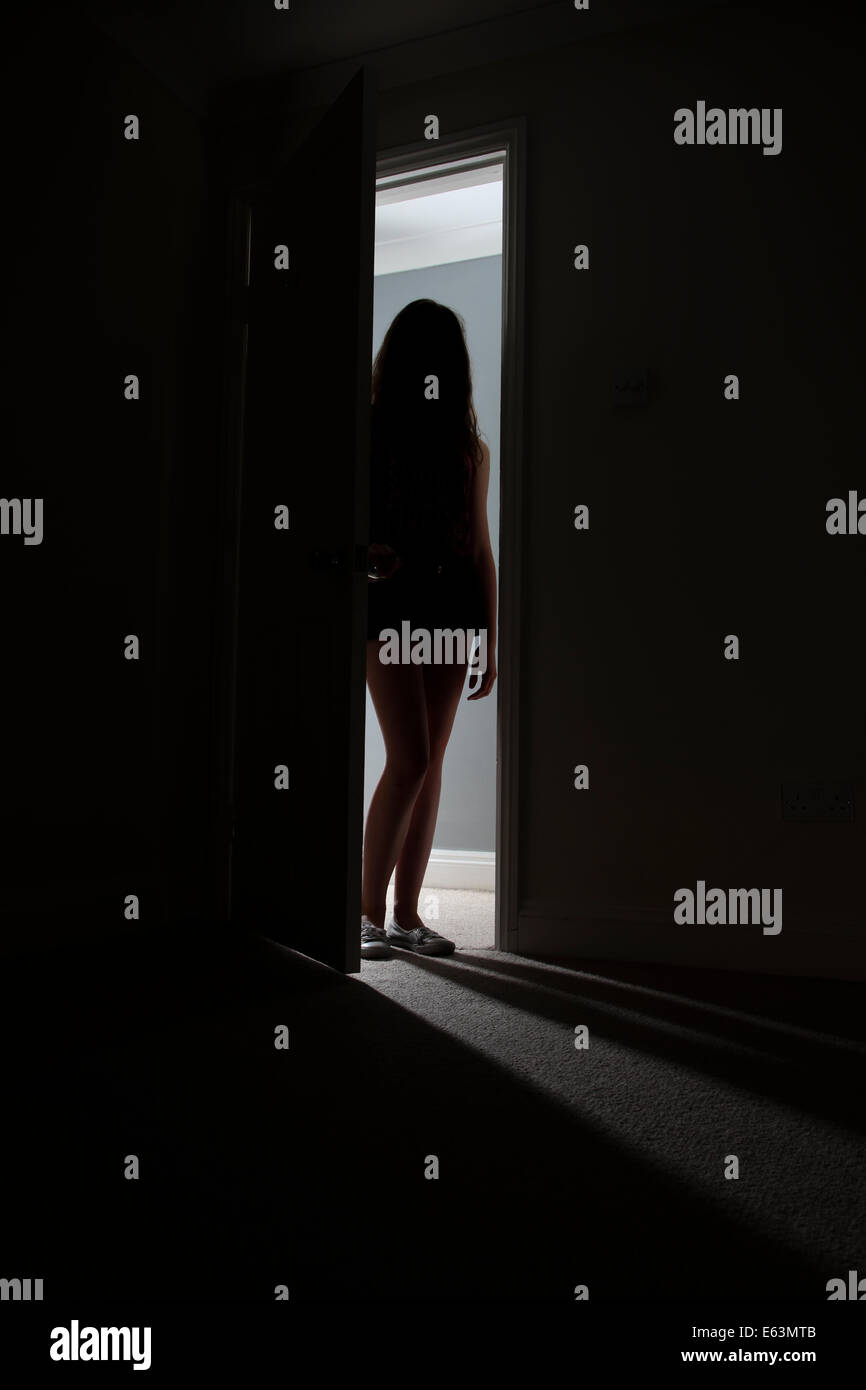 Irriconoscibile silhouette di una ragazza in piedi in una porta. Foto Stock