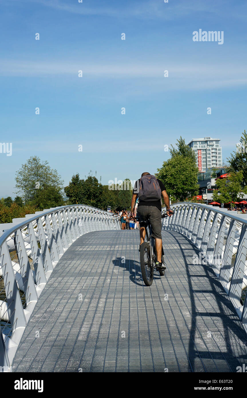 Ciclista attraversando il ponte di Canoa False Creek Village, Vancouver, BC, Canada Foto Stock