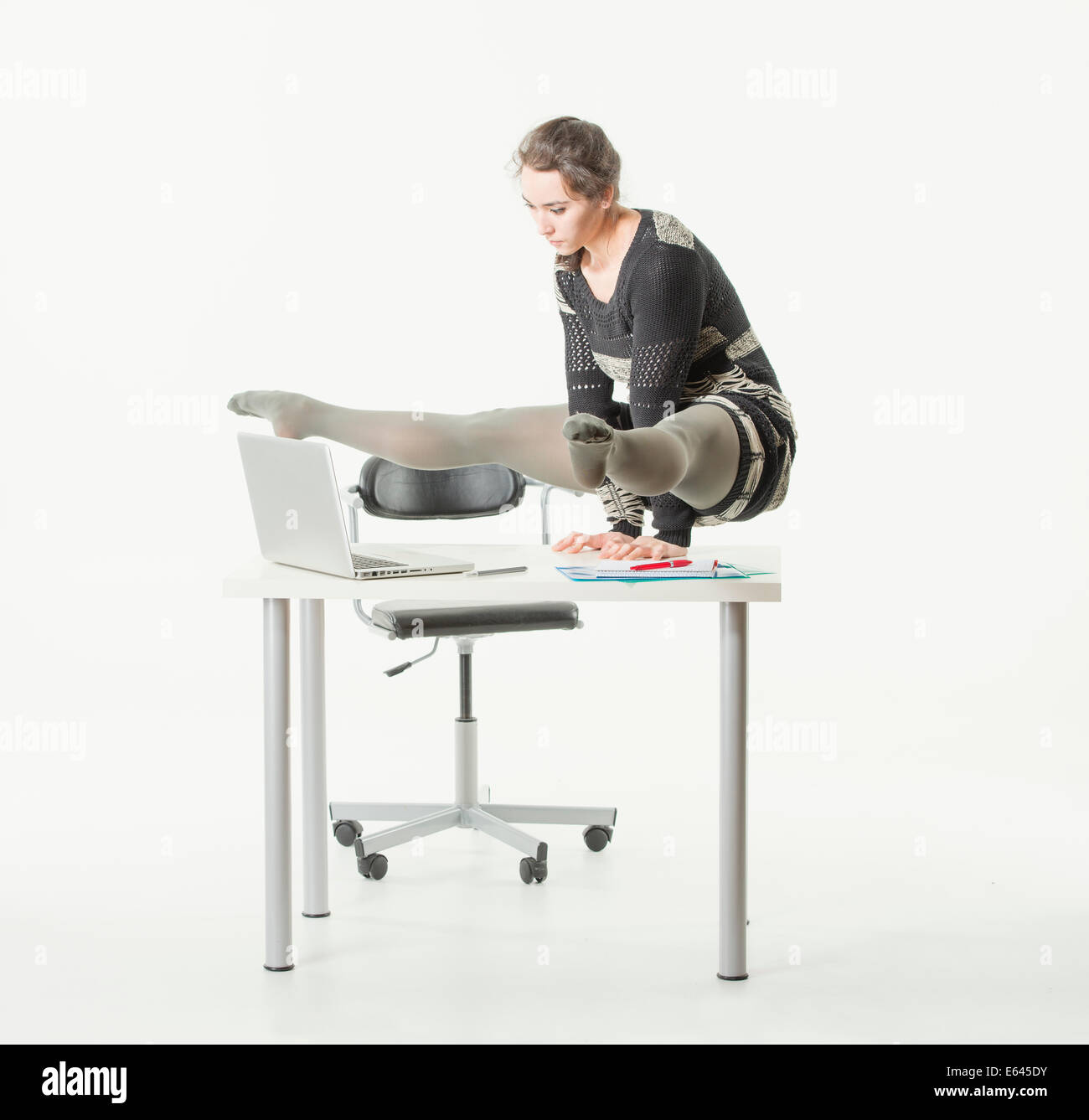Giovane donna in equilibrio su le mani su una scrivania in ufficio mentre guardando il suo computer Foto Stock