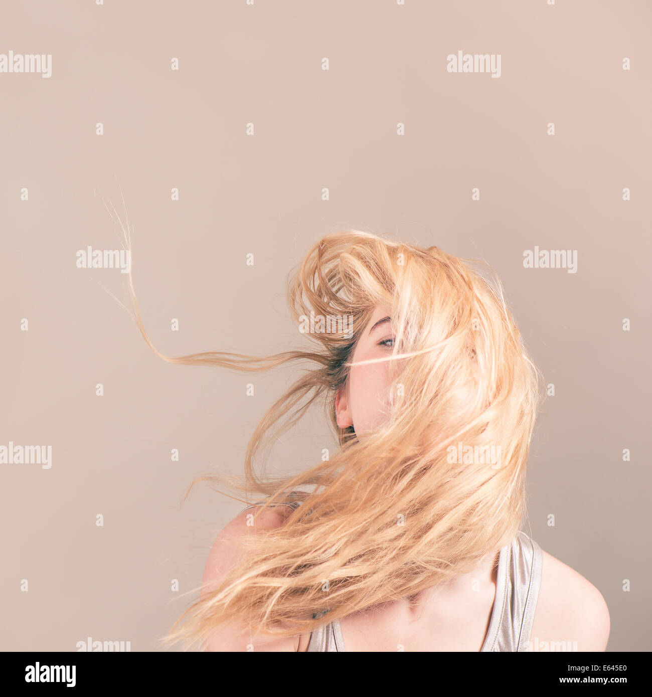 Giovane donna bionda con capelli volare attraverso il suo volto Foto Stock