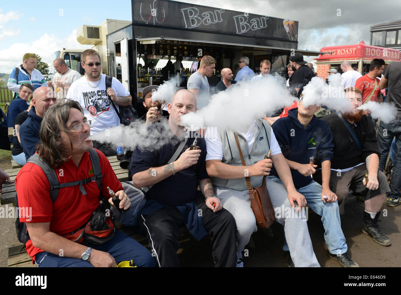 Gli uomini espirando vapore dall elettronica e sigaretta a Vapefest 2014 Foto Stock